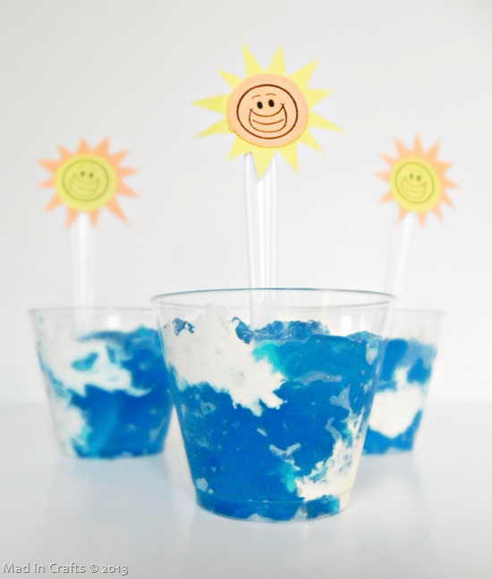 cups of jello and whipped cream holding spoons decorated with paper suns