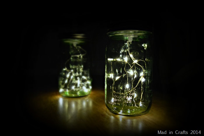 Two green mason jars filled with mini LED lights glowing at night