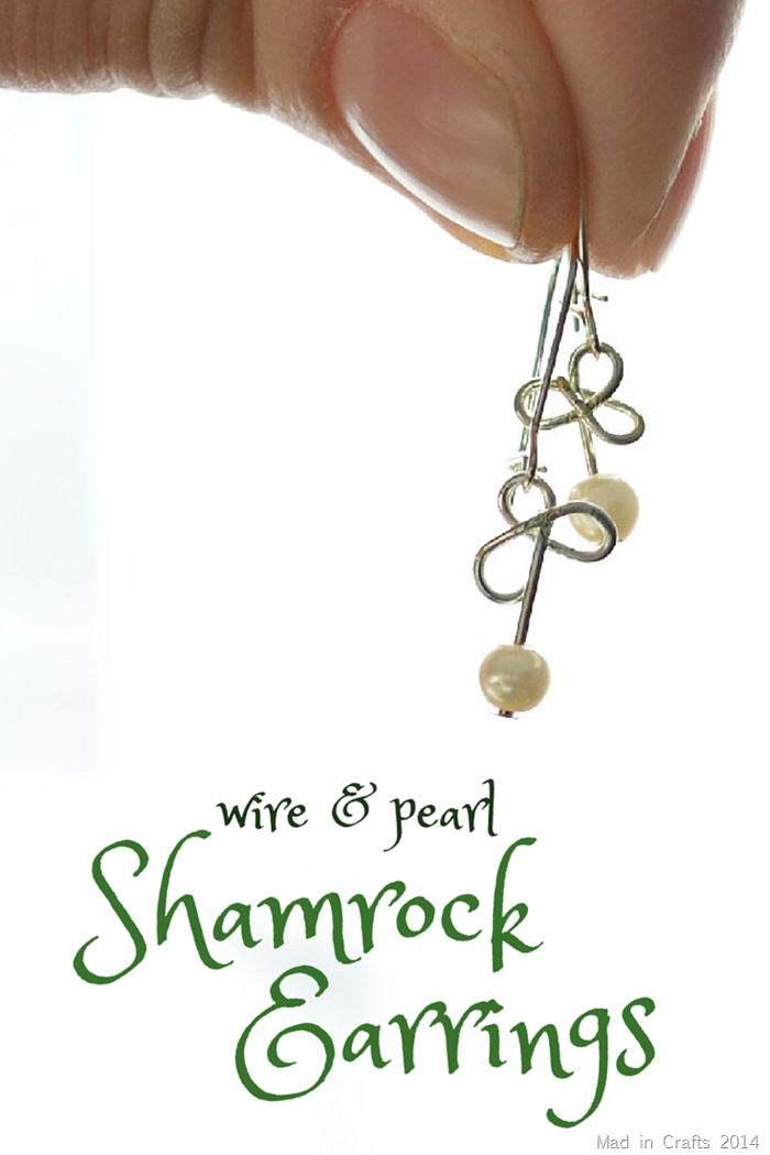 hand holding wire and pearl shamrock earrings on a white background