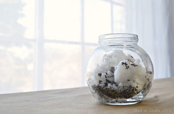 Glass jar containing dried lavender and oil near a window