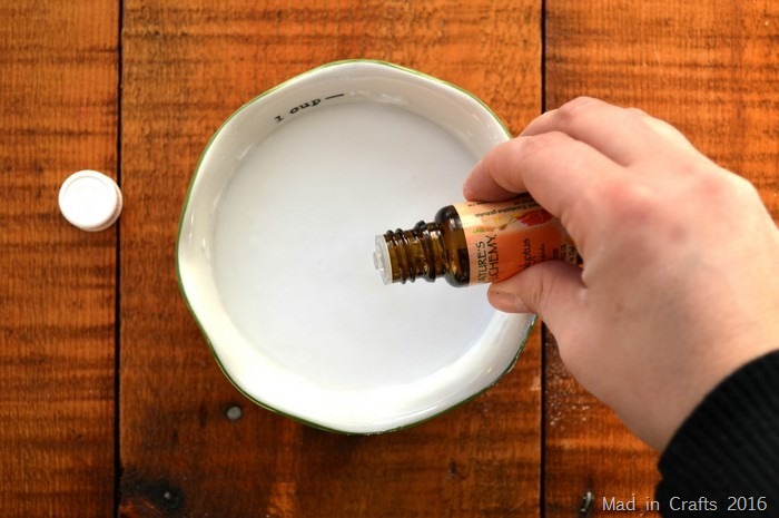 white woman's hand pouring essential oil into a bowl of baking soda