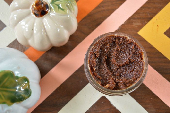 mason jar of pumpkin spice sugar scrub on striped tray with ceramic pumpkins