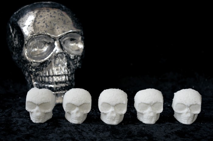 white skull shaped bath bombs on a black background