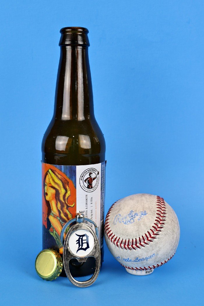 Detroit Tigers bottle opener key chain next to a bottle of beer and a baseball