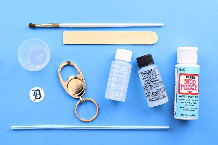 Resin supplies and a bottle opener key chain blank on a blue background