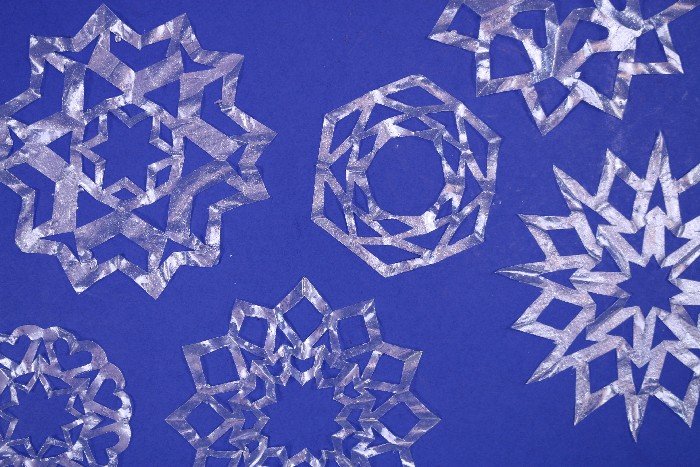 several clear coffee filter snowflake ornaments on a blue background