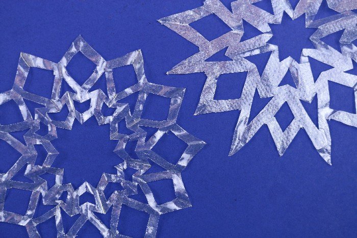 two clear coffee filter snowflake ornament on a blue background