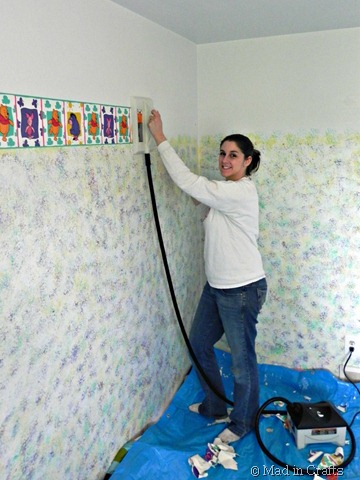 woman removing wallpaper border with a steamer