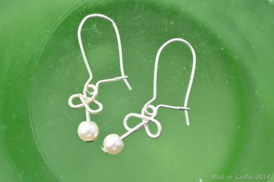 wire and pearl shamrock earrings on a green background