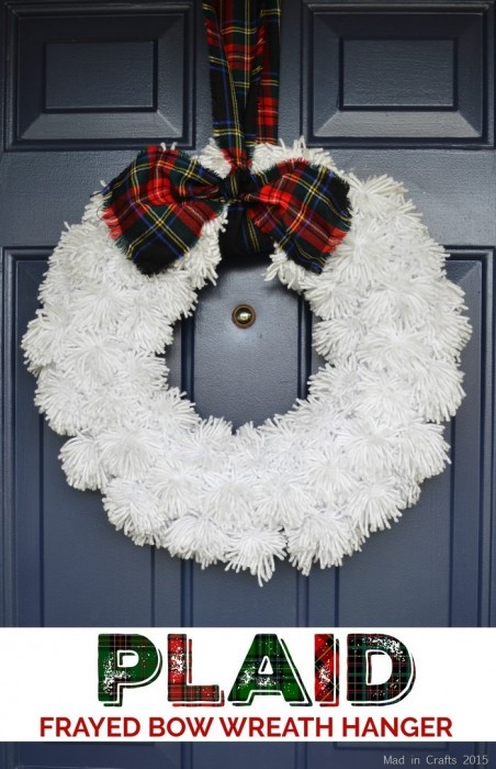 White yarn wreath with plaid ribbon hanging on a blue front door