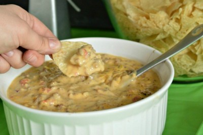 hand holding chip with sausage queso