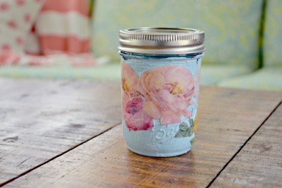 painted mason jar decoupaged with vintage look flowers on a wood table