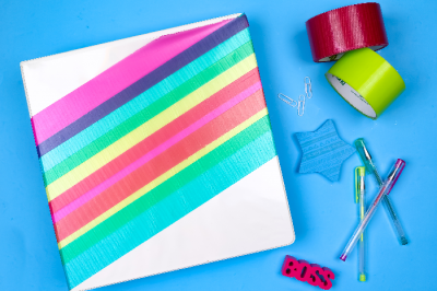 binder with colorful duct tape and school supplies on a blue background