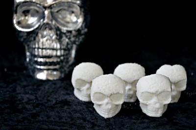 white skull shaped bath bombs on a black background