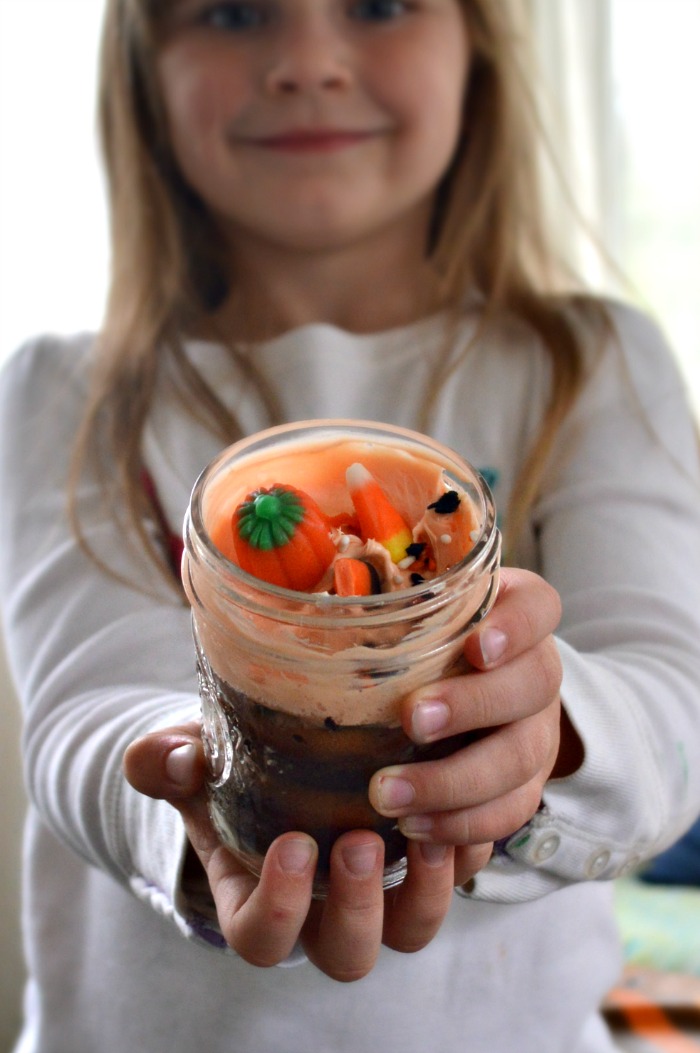 Girl holding a mason jar with Halloween cupcake