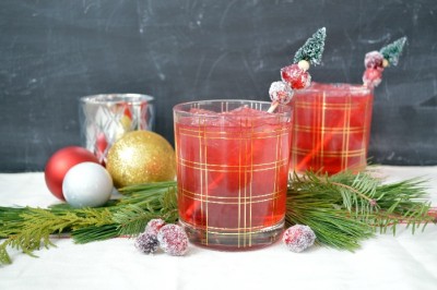 Cranberry cocktails with sugared cranberries next to ornaments and pine swags