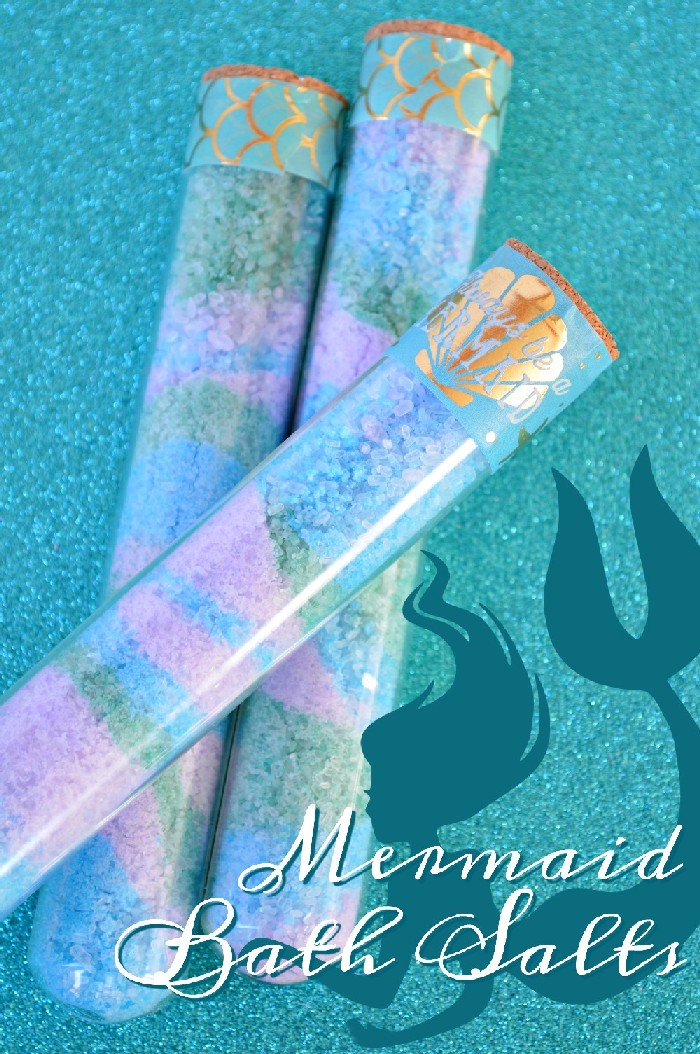 close up of glass tubes with colorful bath salts on a teal glitter background