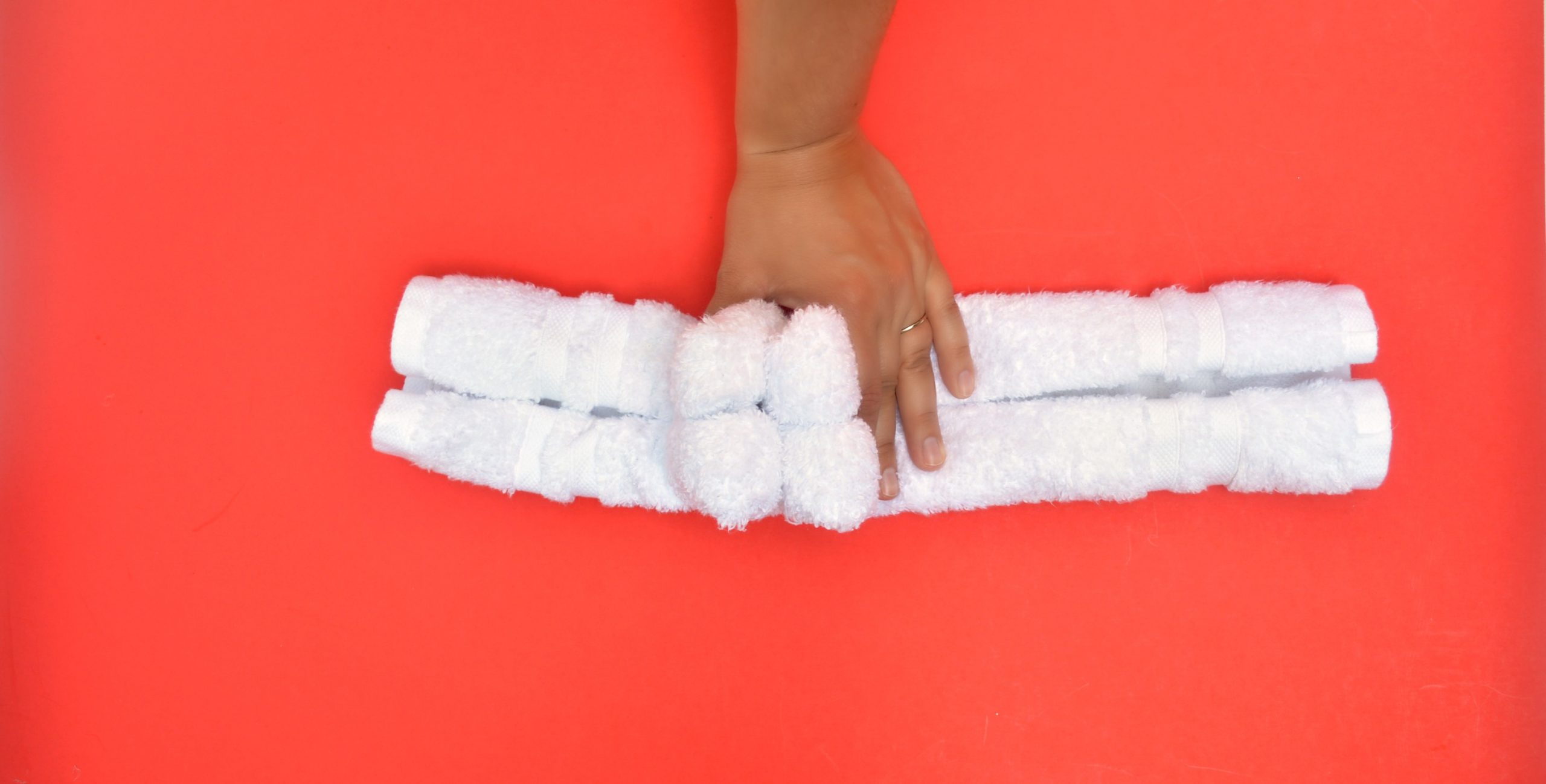 hand folding a towel on a red background
