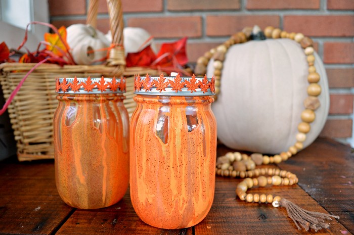 orange and yellow drip painted mason jars next to white pumpkins