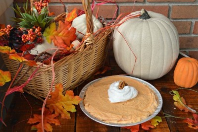 pumpkin cream pie next to a pumpkin and fall leaves