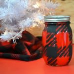 red and black buffalo check painted mason jar next to a white christmas tree