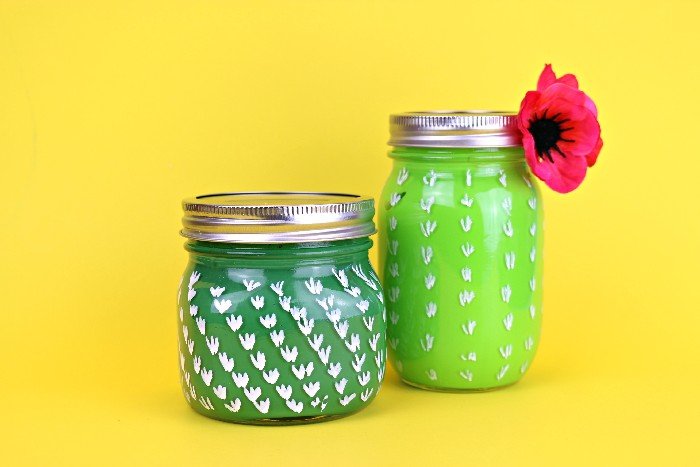 2 cactus painted mason jars on a yellow background