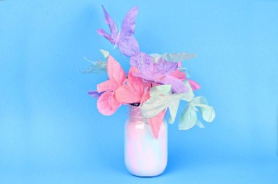 pastel painted mason jar filled with pastel flowers on a blue background