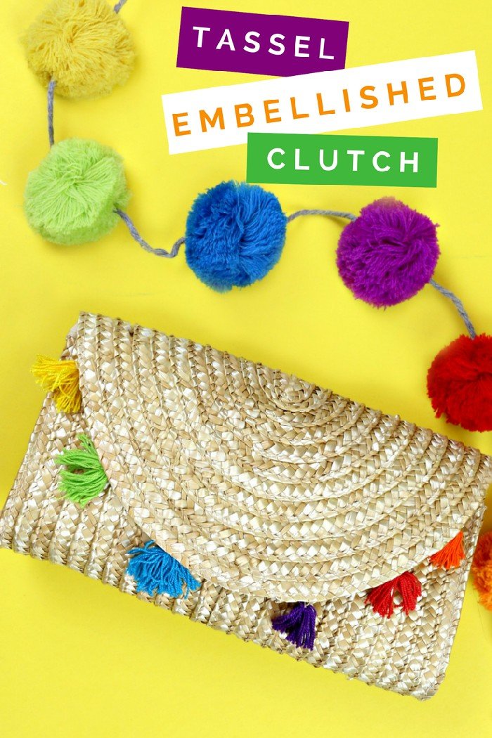 straw clutch with rainbow tassels next to a rainbow pom garland on a yellow background