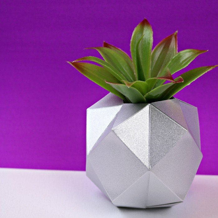 silver geometric paper vase holding a faux succulent