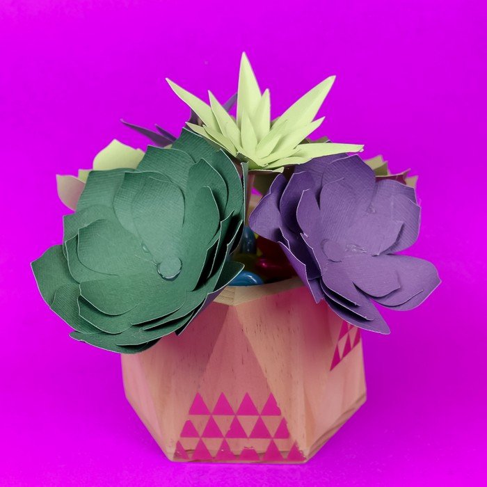 purple and green paper succulents in a vase on a purple background