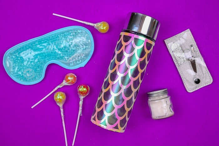 cricut vinyl on a water bottle with eye mask and manicure tools on a purple background