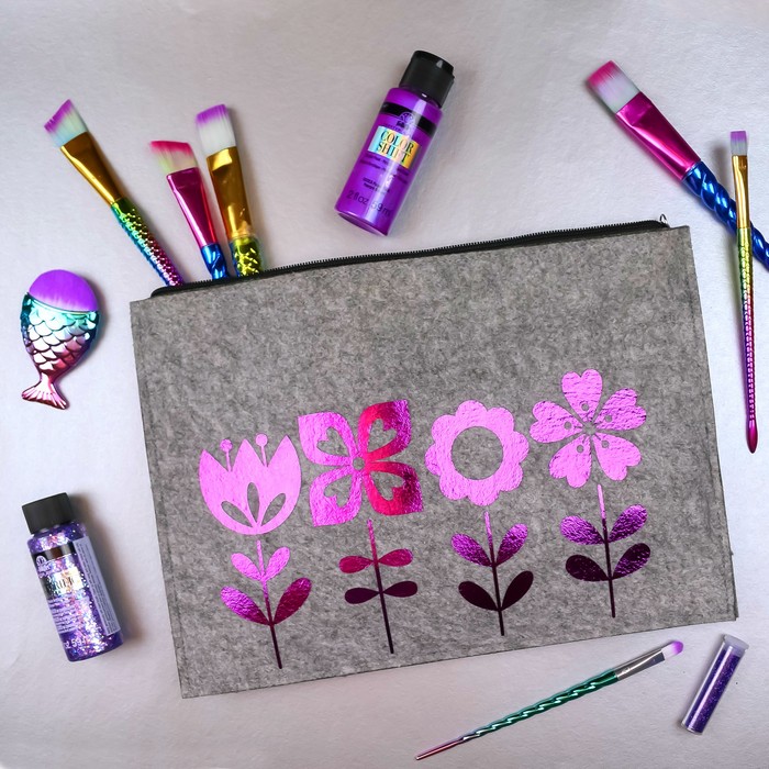 foil vinyl flowers on a zipper pouch with purple craft supplies on a silver background