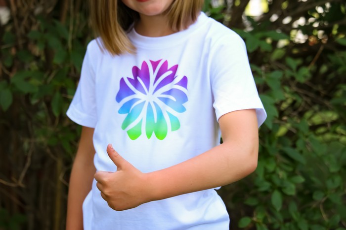 A little girl wearing an infusible ink shirt and giving a thumbs up