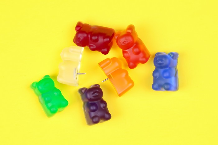 colorful resin gummy bear thumbtacks on a yellow background