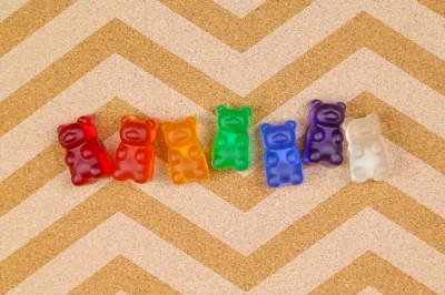 Rainbow resin gummy bear thumbtacks on a bulletin board