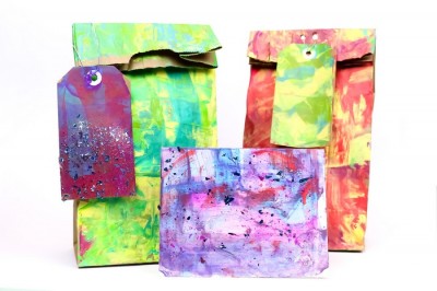 colorfully painted gift bags, tags, and cards on a white background