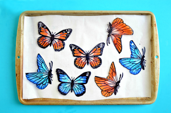blue and orange shrink plastic butterflies on a baking sheet