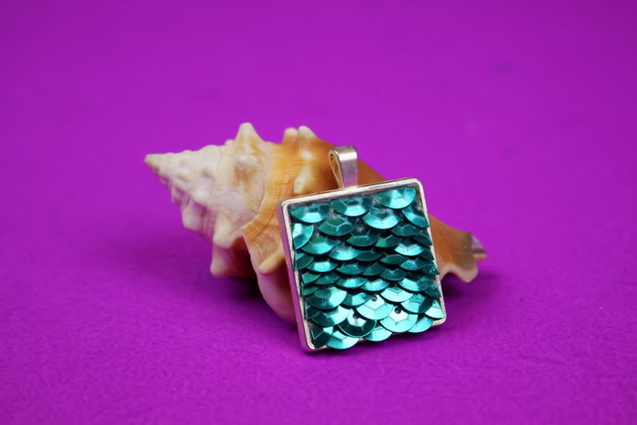 Sequin pendant leaning against a seashell