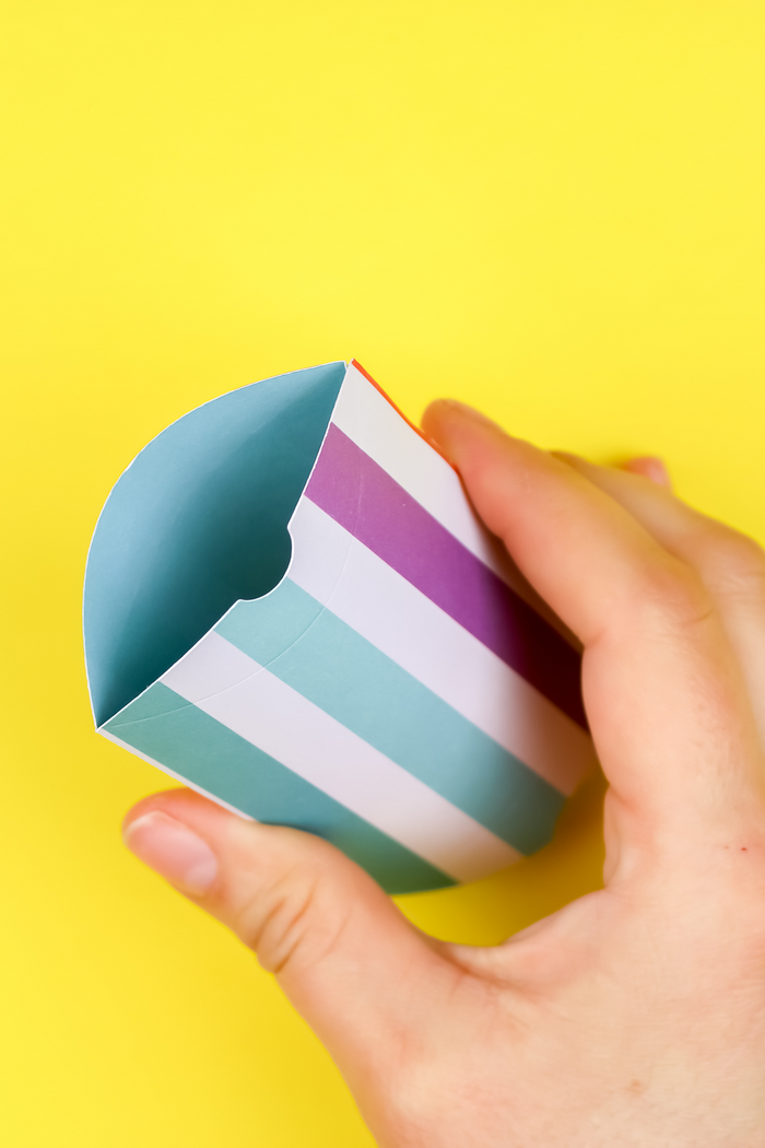 hand opening a colorful pillow favor box