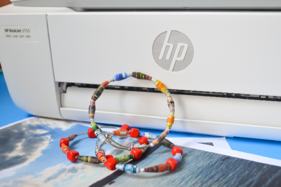 rolled paper beads on bracelets leaned against a printer