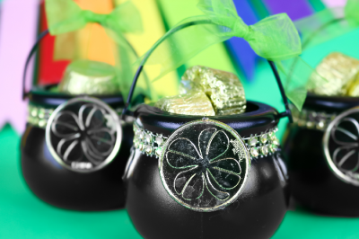 close up of mini pots of gold on a green background with rainbow bunting