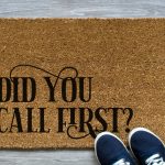 Coir door mat that reads Did You Call First next to navy sneakers