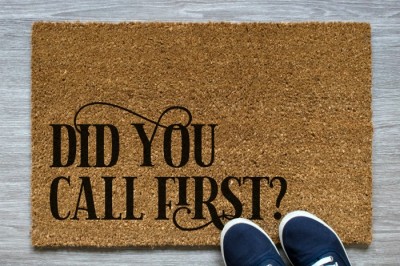 Coir door mat that reads Did You Call First next to navy sneakers