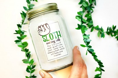 hand holding a mason jar of DIY bath salts with a printable sloth label