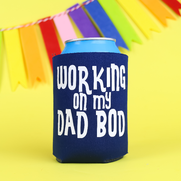 Navy can koozie that says Working on My Dad Bod in white vinyl on a yellow background