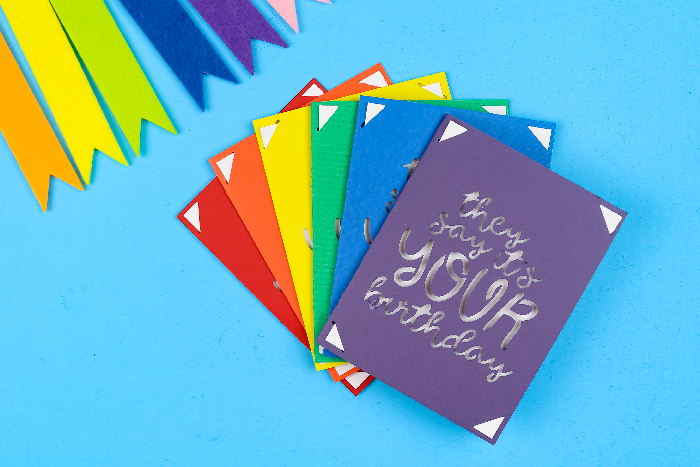 rainbow of Cricut insert cards for birthdays on a blue background