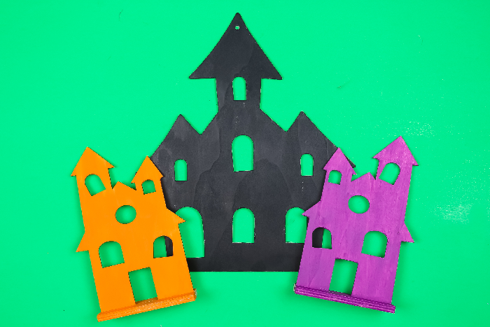 black, orange, and purple halloween houses on a green background