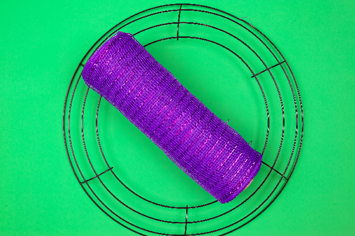 wire wreath form and purple deco mesh on a green background