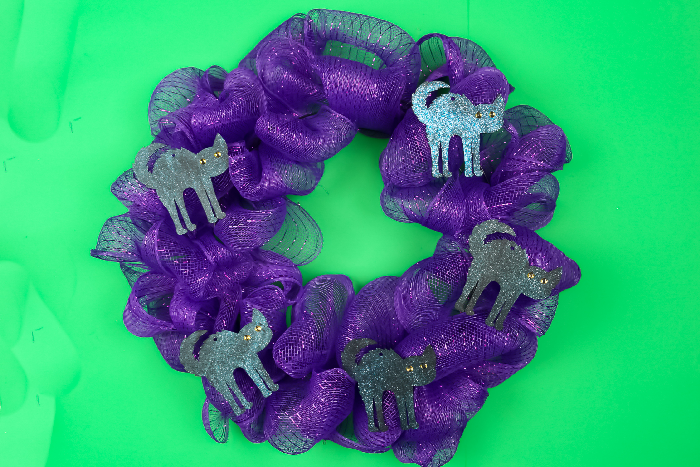 Halloween purple mesh wreath with cat shapes on a green background