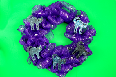 purple mesh wreath with black cat shapes and rhinestones on a green background